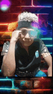 a man wearing a headband and sunglasses is sitting in front of a neon brick wall