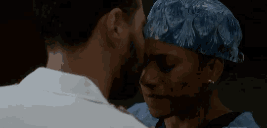 a man and a woman are kissing and the woman is wearing a blue scrub cap