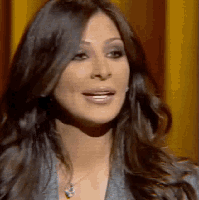 a woman with long dark hair wearing a necklace