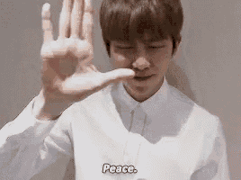 a young man in a white shirt and tie is making a peace sign with his hands .
