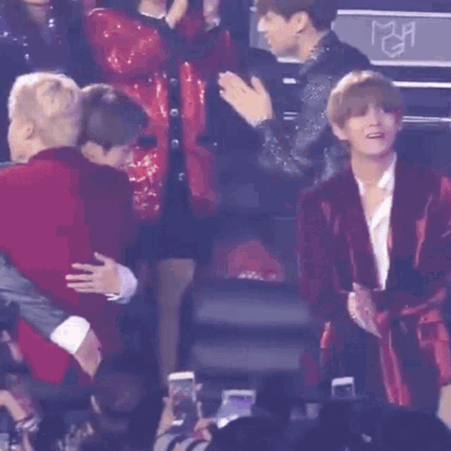 a man in a red sweater is hugging another man in a black jacket