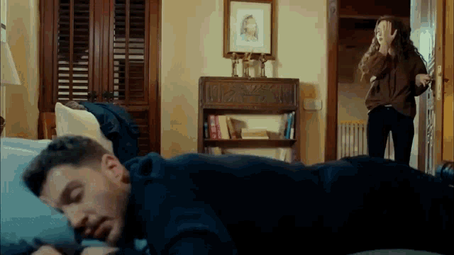 a man is laying on his stomach on a bed while a woman stands behind him .