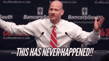 a man in a white shirt and red tie is standing in front of microphones with his arms outstretched and says this has never happened