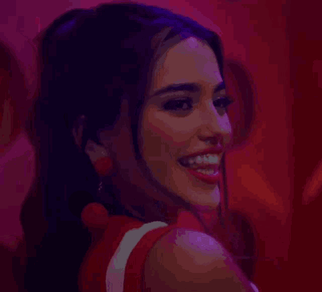 a woman in a red dress is smiling and looking over her shoulder