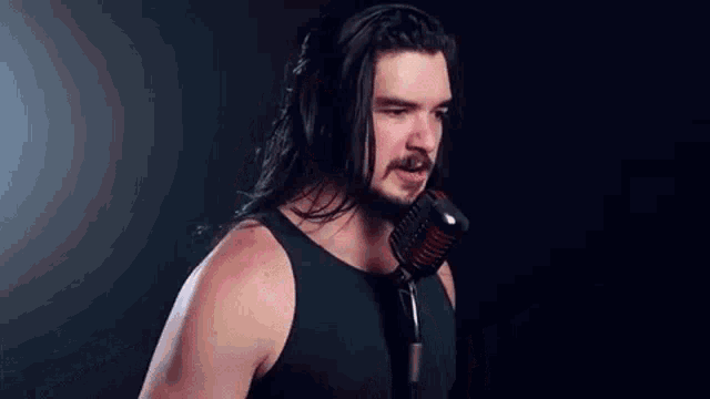 a man with a beard is singing into a microphone .
