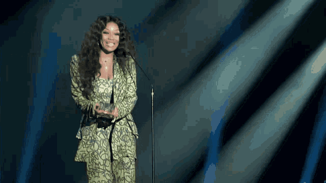 a woman in a green suit is holding an award