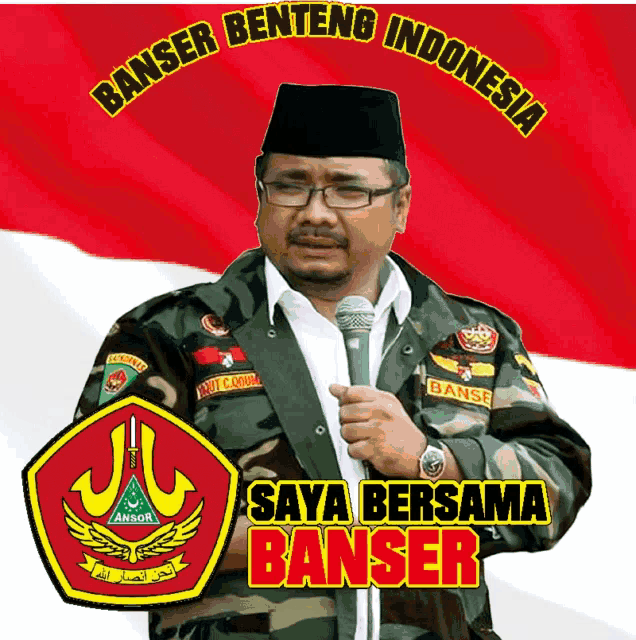a man holding a microphone in front of a banner that says saya bersama banser