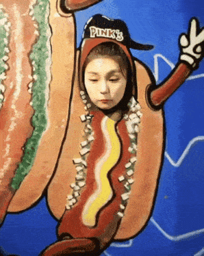 a girl in a hot dog costume with pink 's hat on her head