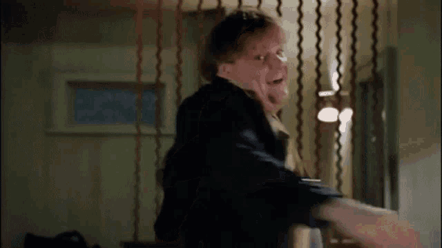 a man is being punched in the face in a room with a curtain .