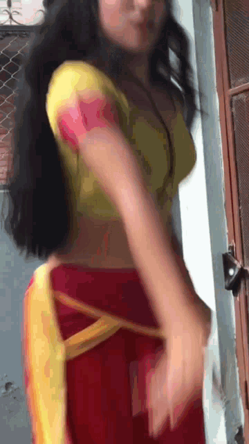 a woman wearing a yellow top and red pants is standing in front of a door