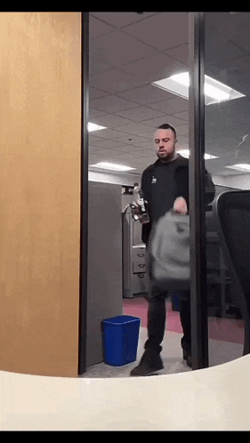 a man in a black jacket is walking through a glass door holding a briefcase