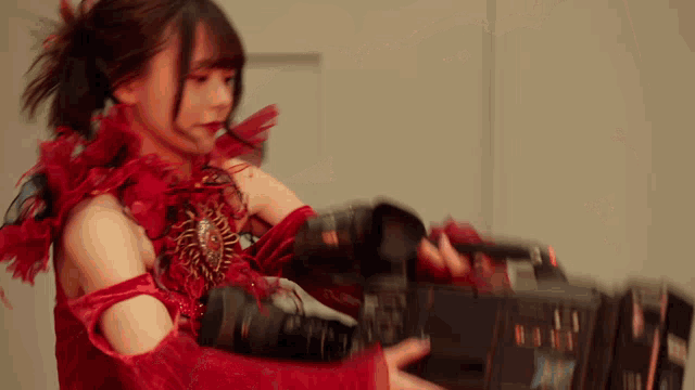 a girl in a red dress is holding a camera