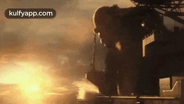 a giant gorilla is standing on top of a building in front of the sun .