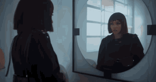 a woman is looking at herself in a round mirror