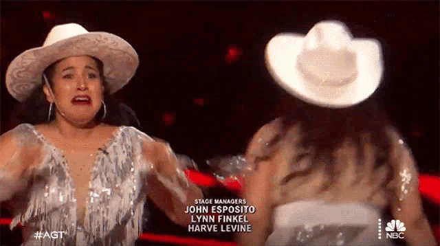 a woman wearing a cowboy hat stands next to another woman wearing a dress