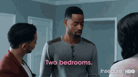 two men and a woman are standing in a room and one of them is saying two bedrooms .