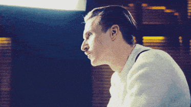 a man wearing a white sweater looks to his left