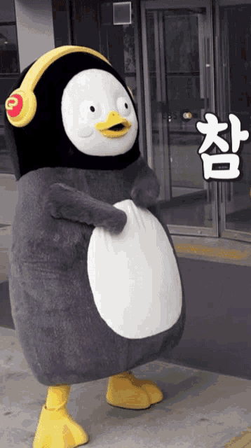 a stuffed penguin wearing headphones stands in front of a door