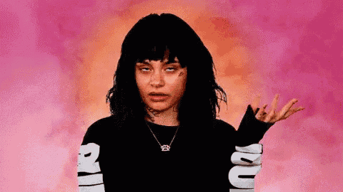a woman with black hair is making a funny face while wearing a black shirt with snake sleeves .