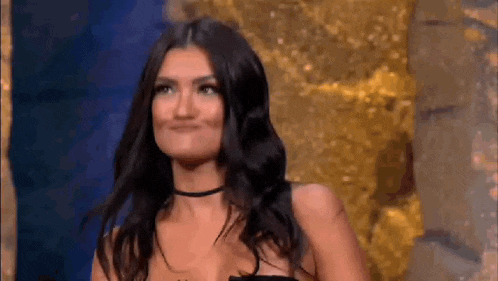 a woman in a black dress is standing in front of a gold statue and smiling .