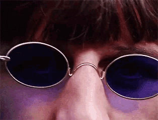 a close up of a person wearing a pair of round sunglasses