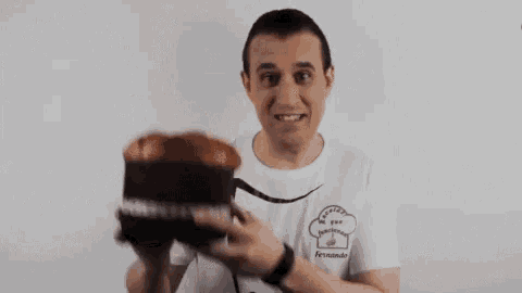 a man in a white shirt is holding a large panettone in his hands .