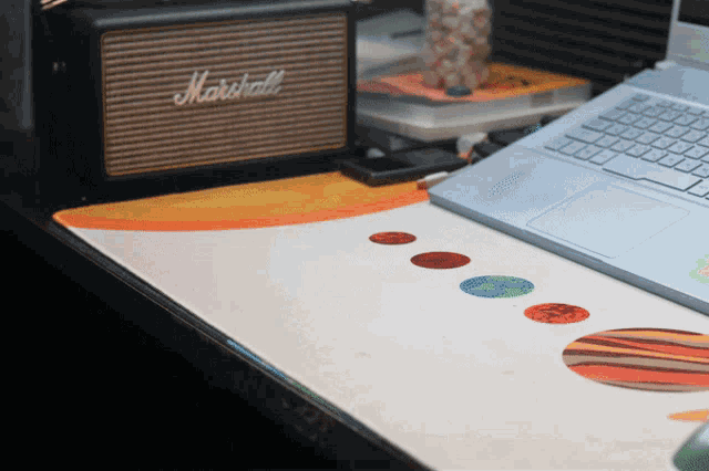 a marshall speaker sits next to a laptop computer