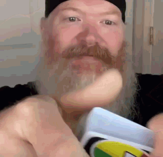 a man with a beard and mustache is holding a card in his hand .