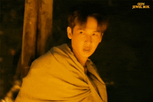 a man in a yellow blanket stands in front of a gun jewel box