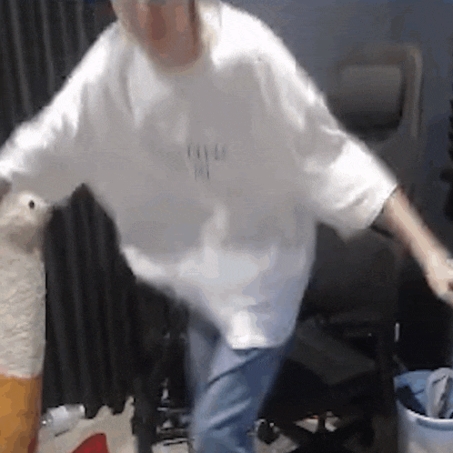 a man in a white shirt and blue jeans is standing in a room with his arms outstretched .