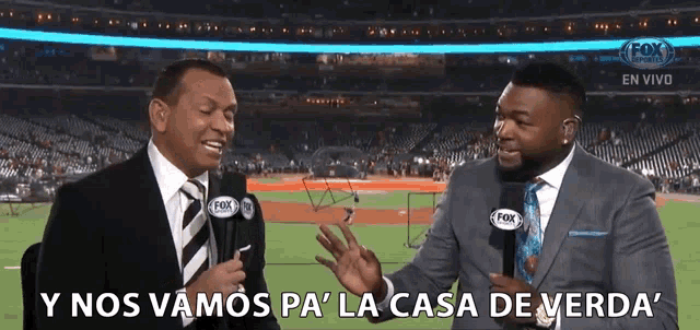two men in suits are talking to each other in front of a fox stadium