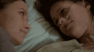 two women kissing in a hospital bed with an oxygen tube
