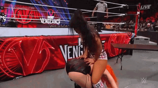 a woman is wrestling in a ring with a banner that says vengeance
