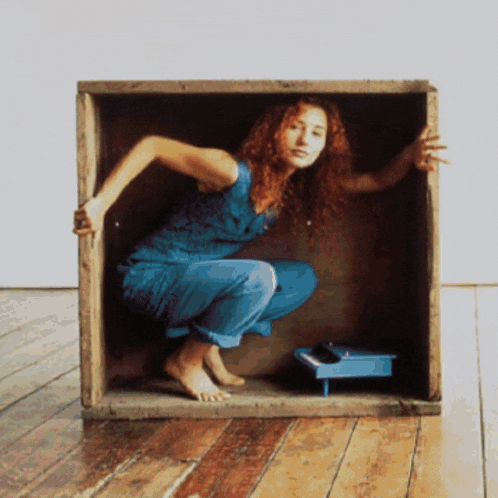 a woman is squatting in a wooden box