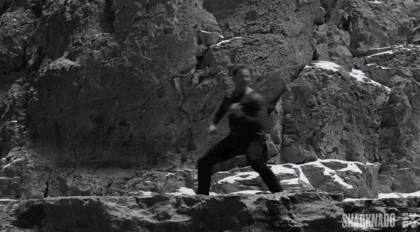 a man is climbing a rock wall with the words sharknado on the bottom right