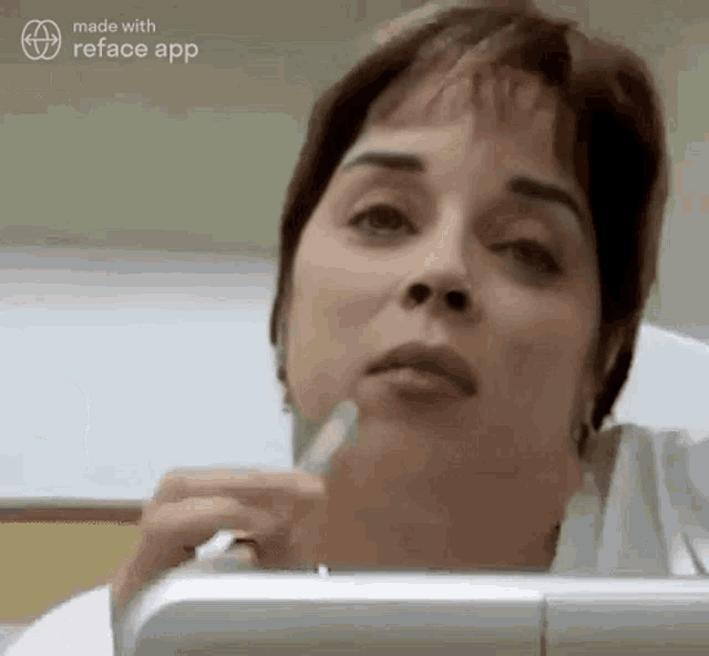 a woman is sitting at a desk with a pen in her mouth .