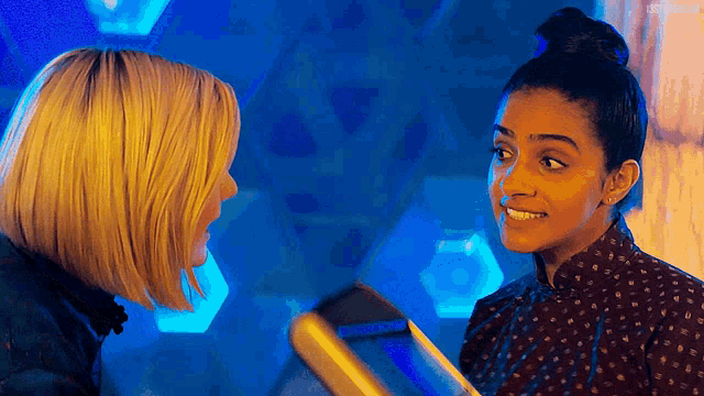 two women are standing next to each other in front of a blue background .