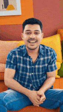 a man in a plaid shirt sits on a couch