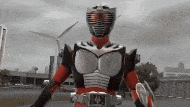 a man in a red and black superhero costume is standing in front of a windmill in a video game .