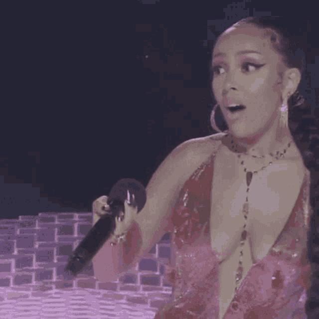 a woman in a very plunging pink dress holds a microphone