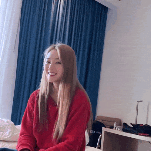a woman in a red sweater is sitting on a bed