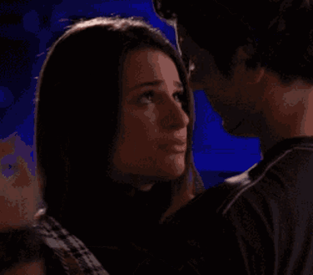 a man is touching a woman 's forehead while they kiss .