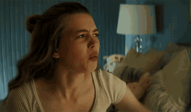 a woman is making a funny face in front of a bed