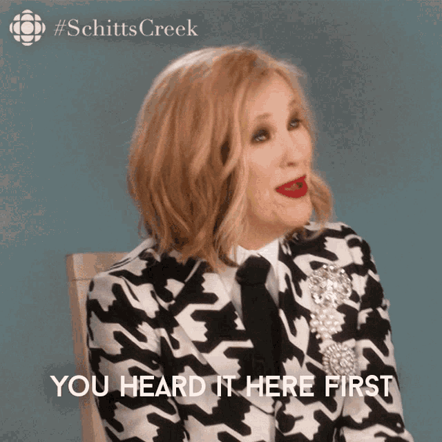 a woman wearing a black and white suit and tie says you heard it here first