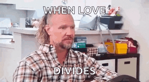 a man in a plaid shirt is sitting at a table with a ponytail .