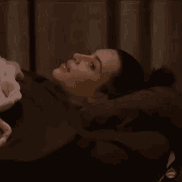a woman is laying in a bed with a blanket on her head