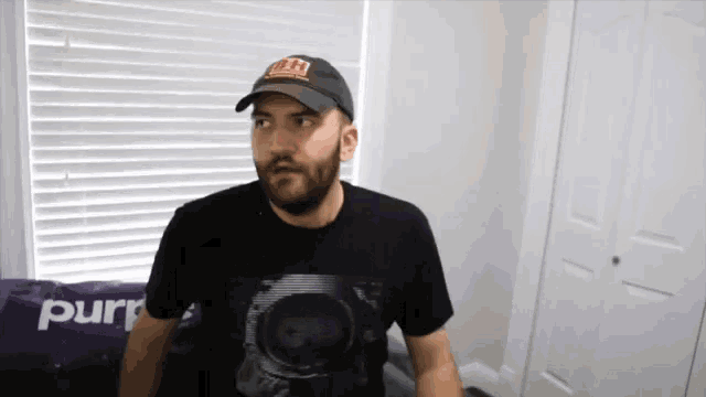 a man wearing a hat and a t-shirt that says purr on it