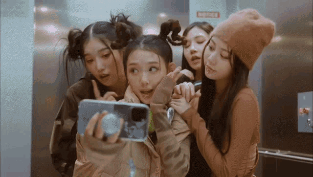 a group of girls are taking a selfie in front of a notice sign