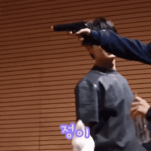 a man is pointing a gun at another man 's face while another man looks on .