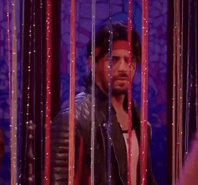 a man wearing a bandana and a leather jacket is behind a row of ribbons .